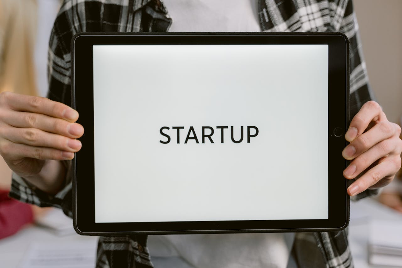 Crafting Captivating Headlines: Your awesome post title goes here Person holding a digital tablet displaying the word 'STARTUP', representing new business concepts.
